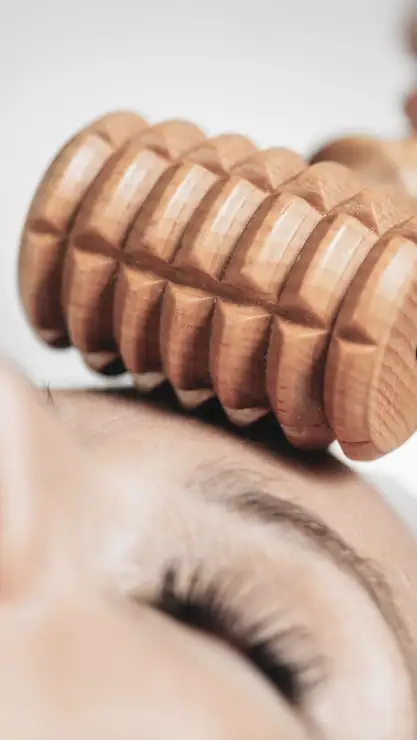 Mujer sonriendo sujetando una bonita flor rosa cerca de su cara representando que tiene una buena higiene facial