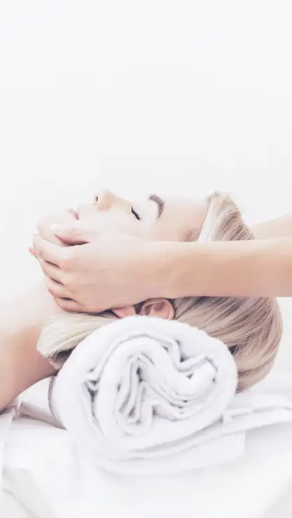 Primer plano de cara de una mujer relajada recibiendo un masaje craneofacial