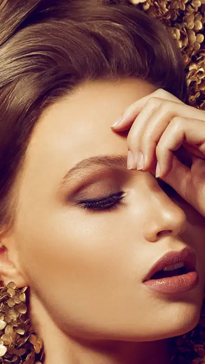 Rostro de mujer con piel muy dorada sobre pepitas de oro.