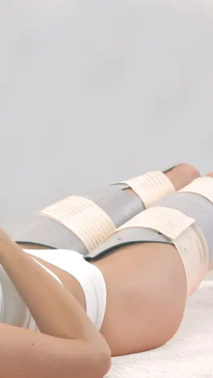 Mujer tumbada recibiendo un tratamiento corporal con electroestimulación