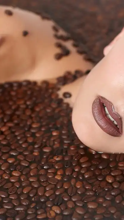 Primer plano de los labios de una mujer sumerguida en granos de café